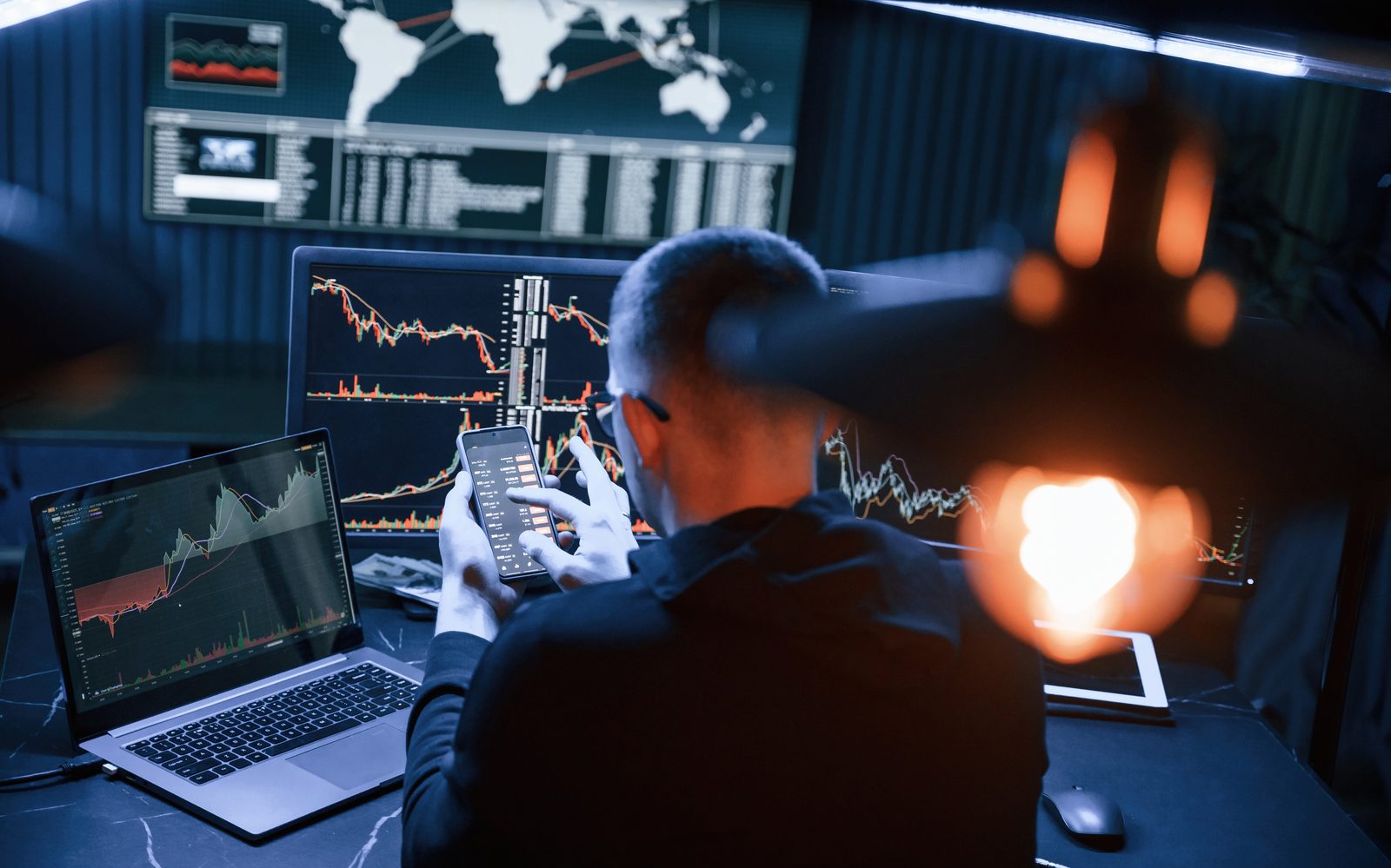 A trader's desk with multiple screens showing live market charts